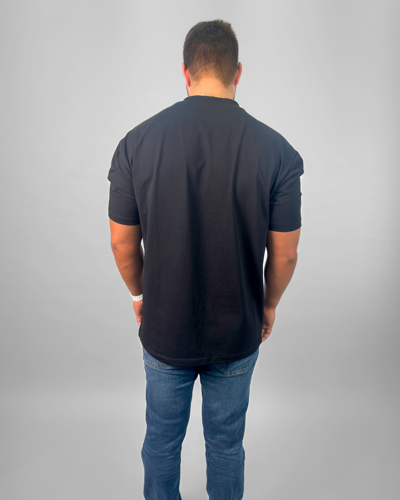 Man wearing a black t-shirt and blue jeans on a gray background